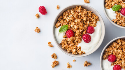 Granola with yogurt and raspberries in bowls, white background.