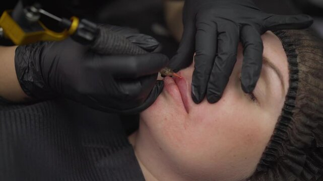 Cosmetologist applying permanent makeup on lips of client.