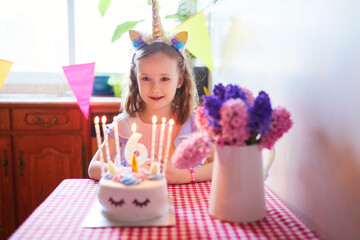 Happy little girl celebrating her sixth birthday and making a wish. Little kid with birthday cake and candle