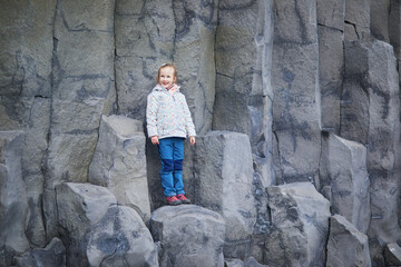 Adorable preschooler girl having fun on Reynisfjara Black Sand beach near Vik in Iceland