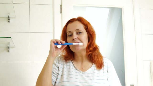 Woman brushes her teeth in the bathroom