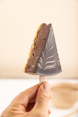 Chocolate and Vanilla Cake pops Marshmallow with hand with cup of coffee on white wooden, side view, selective focus.