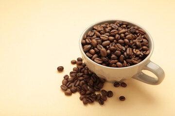 Coffee beans in coffee cup on beige background.