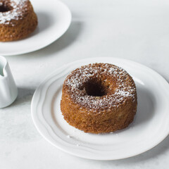 mini vanilla bundt cakes on a white plate, vanilla bundlette with icing sugar on a white background, homemade small vanilla bundt cakes