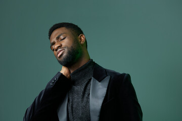Confident young businessman in a black suit smiling with hands on head, expressing relief and satisfaction