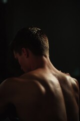 Naklejka premium A young man with athletic build looking at his reflection. A picture of dedication and physical fitness.