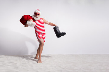 Obraz premium Photo of cheerful santa claus in red striped swimsuit sunglass vacation on island with white sandy beach