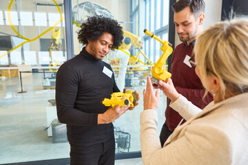 Engineers discussing and programming robotic arms for industrial automation