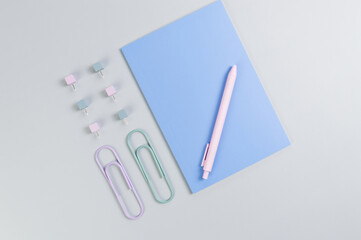 Top view of blue notebook on grey background. Paperclips, pen and pins. School, office wallpaper. Flat lay, copy space.