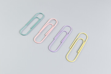 Top view of colorful paperclips on grey background. School, office wallpaper. Flat lay, copy space.