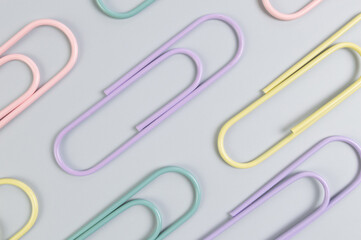 Top view of colorful paperclips on grey background. School, office wallpaper. Flat lay, copy space.