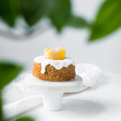 Iced mini bundt cake on a white plate, vanilla bundlette with a clementine segment on a plate, small vanilla bundt cake with an icing glaze