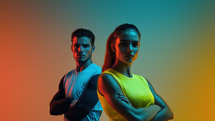 Two focused athletes stand in vibrant colored lights.