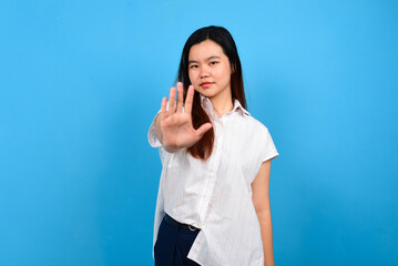 Stop. Concerned Asian woman showing refusal sign with crossed arms, saying no, raise awareness, standing and isoltaed on blue bright background, copyspace