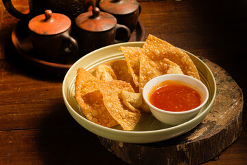 crispy chicken wonton on white bowl. Served on wooden table and chili sauce a side. Perfect for menu, catalogue or commercial use purpose