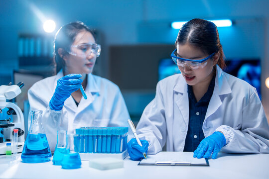 Two young female scientists working with test tubes in a modern laboratory setting