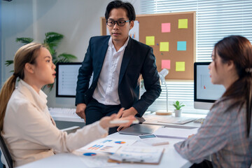Three people are sitting at a table with a computer monitor in front of them