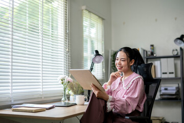 A woman is sitting at a desk with a tablet in front of her