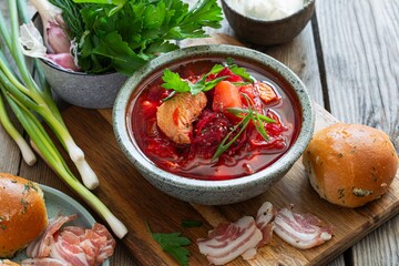 National dish of Ukrainian cuisine borscht with vegetables, turkey meat, herbs, sour cream and traditional bread (bun with garlic and dill, pampushka) with bacon (pork). Cultural heritage.
