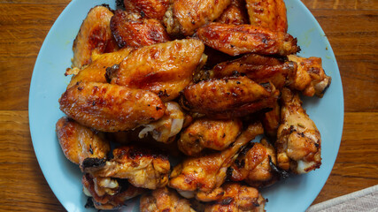 Chicken wings baked in the oven on a plate on a wooden table top view