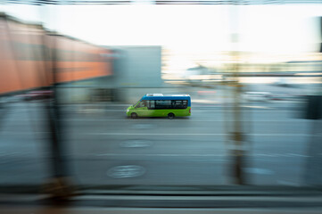 A vibrant green bus speeds through an urban street, captured with dynamic motion blur highlighting its rapid movement against a city backdrop...