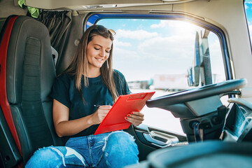 Portrait of beautiful young woman professional truck driver sitting and resting after long drive....