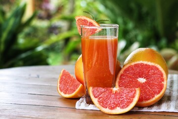 Grapefruit juice (Citrus × paradisi) with Heap of sliced,half and whole of its put on wooden table...