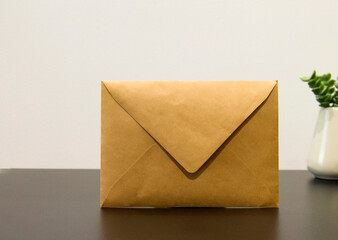 Blank kraft paper envelope on black wooden table.