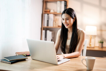 Young happy cheerful cute beautiful  woman sit indoors in home office with laptop computer