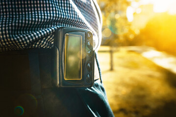 Man wearing pager on his belt. Shot with sun flares. Selective focus