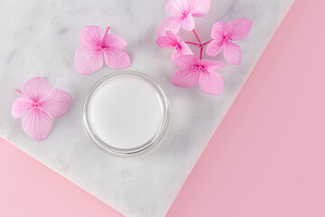 Cosmetic jar with natural colorless lip balm on a marble flower podium. pleasant aroma. Perfect for makeup. top view. copy space. Care, beauty concept