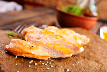 Grilled chicken breast with spice rub and lemon on a cutting board, sliced and whole