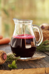 Red beet juice in a glass jug on a table outdoors