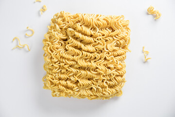 uncooked instant noodles with pieces of instant noodles around, texture of dry instant noodles on white background