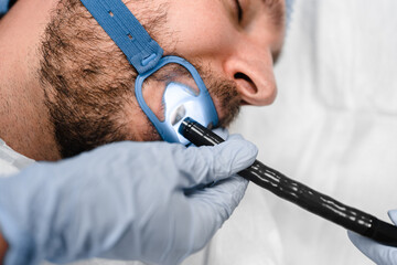Gastroscopy endoscopy. Cropped of male patient during gastroscopy. Man laying at the bed while...