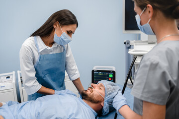 Female doctor checking to patient before endoscopy colonoscopy examination in modern clinic, nurse...