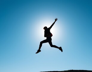 Fototapeta premium A person jumps high into the air, their body fully extended in mid-motion, creating a dynamic silhouette against a crisp, clear blue sky.