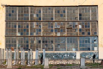 An old technical building with a large window made of different glasses in the industrial area of...