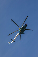 Fototapeta premium The helicopter flies in cloudless weather with a blue sky. Air transport.