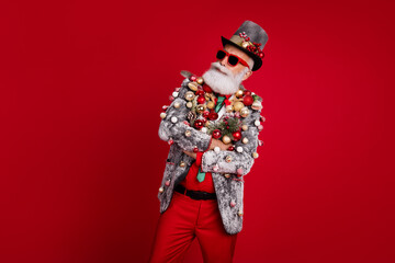 Photo of cheerful positive grandfather santa dressed jacket arms folded celebrating noel emtpy space isolated red color background