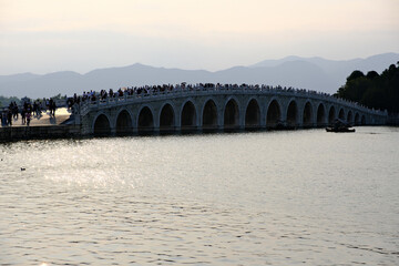 Fototapeta premium Seventeen-Arch Bridge with many tourists in Summer Palace in Beijing, China 