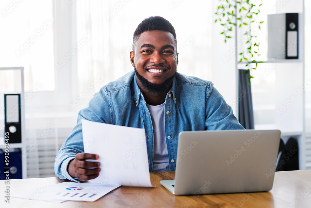 Aufkleber smiling african american businessman working with laptop and documents in office and looking at came