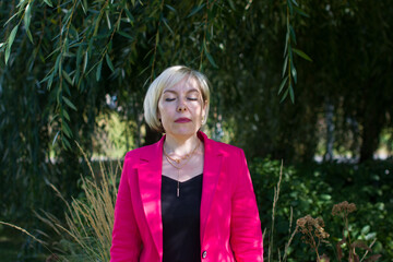 Portrait of a woman in a pink jacket with her eyes closed. Stylish business woman