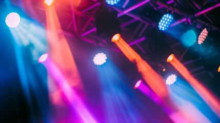 Fototapeta premium Vibrant stage lights in hues of pink, blue, and orange, capturing the energetic atmosphere of a live performance or event.