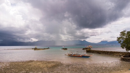 Obraz premium boat aground at low tide in the sea, tropical coast, rainy and typhoon season, Philippine boat