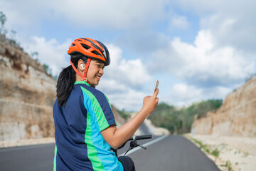 female biker using phone when riding bike, rear view