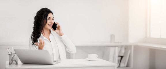 Talkative Girl. Happy latin businesswoman speaking with her friend on mobile phone at work....