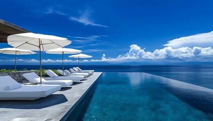 Fototapeta premium Luxury infinity pool overlooking the ocean with loungers and parasols.