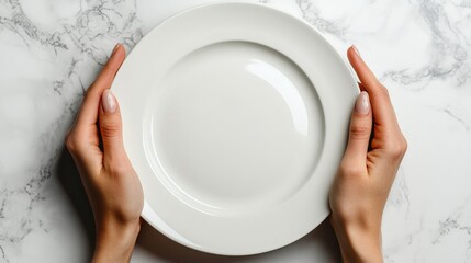 Overhead view of hands holding an empty white plate on a white surface.