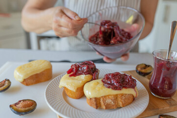 Delicious baked cheese sandwich with homemade plum chutney prepared by woman´s hands in the kitchen